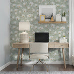 A tastefully decorated home office with the Watercolour Magnolia Wallpaper, showcasing elegant white magnolia blossoms on a pale green background, providing a serene and inspiring environment for work and creativity, accented by natural wood furniture and soft lighting.