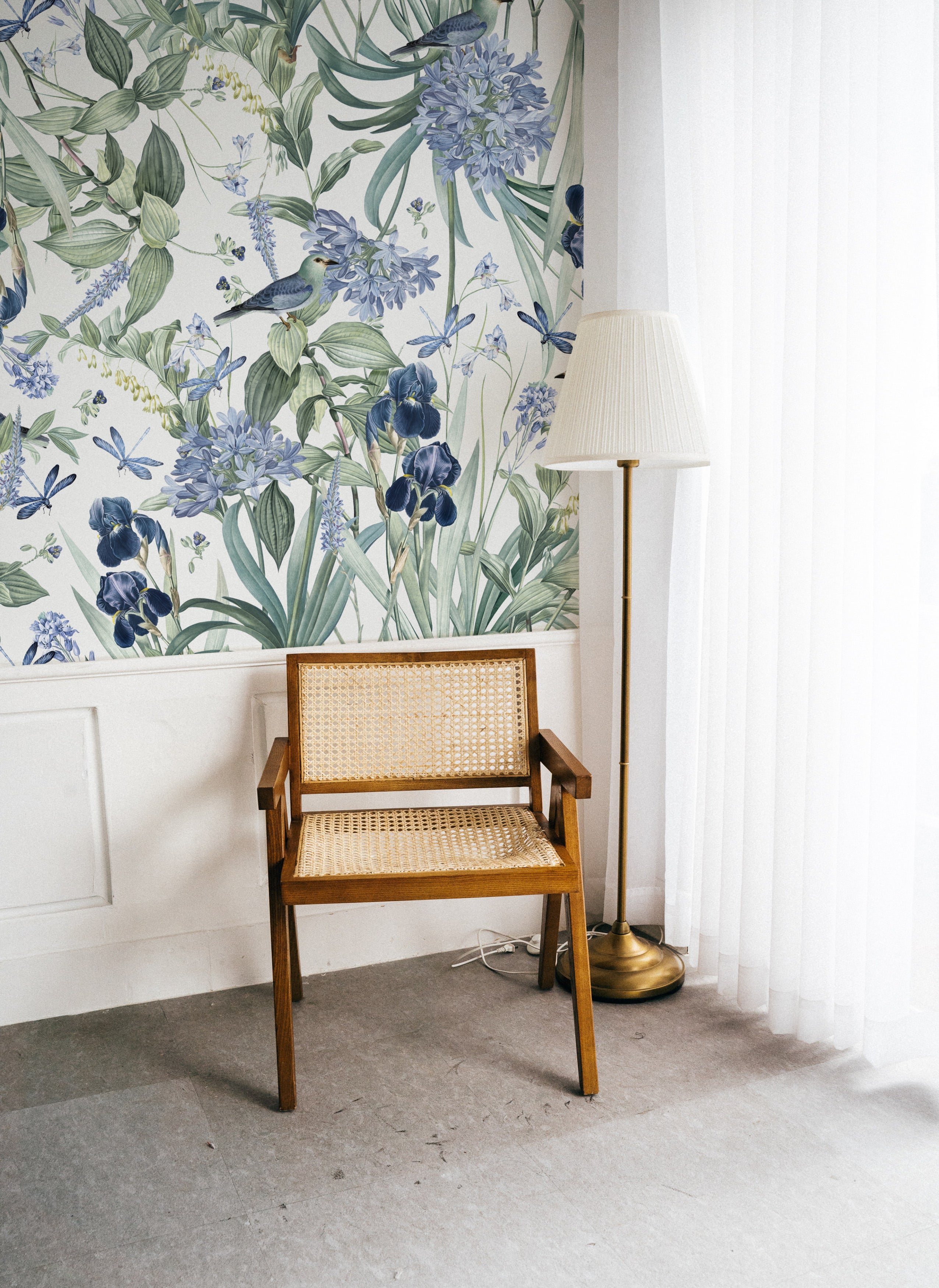 A cozy reading nook with the 'Mint Floral Wallpaper - 50"' adorning the wall, accompanied by a vintage wooden chair with wicker seating and a classic floor lamp, creating an inviting and warm atmosphere.