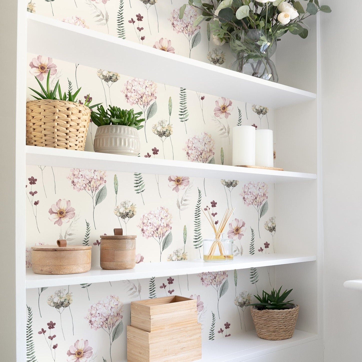 A bright and airy space featuring the Delicate Hydrangea Wallpaper on the wall behind white shelves adorned with potted plants and decorative items, contributing to a peaceful and natural atmosphere.