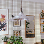  A cozy dining room scene featuring the Plaid Wallpaper - Linen on the walls, lending a comforting and stylish backdrop to the room. The linen-colored plaid pattern adds a touch of rustic charm to the space, harmoniously complementing the wooden furniture, industrial-style pendant lamps, and eclectic wall art and mirrors, creating an inviting space that feels like home.