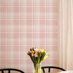 A sunlit dining area featuring the "Plaid Wallpaper - Original" with a classic pink plaid pattern. A clear vase of fresh tulips sits on a wooden table, adding a natural element to the space that complements the wallpaper’s soft, inviting colors.
