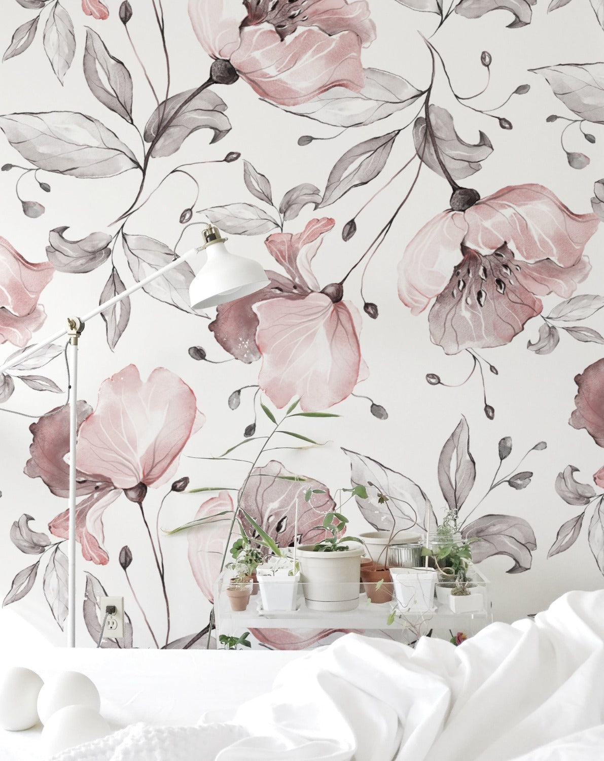 A cozy bedroom featuring Pink Watercolour Floral Wallpaper with delicate pink and grey watercolor flowers and leaves, creating a serene and elegant ambiance